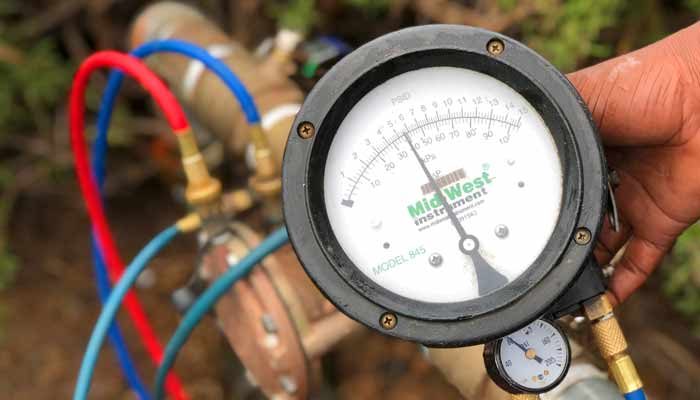 Differential pressure test gauge connected to a backflow assembly during a test